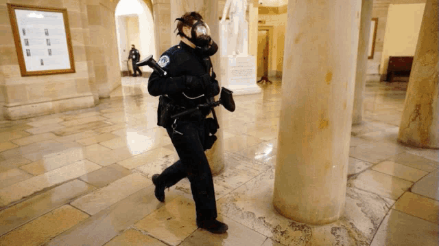 a police officer wearing a gas mask and holding a gun in a building