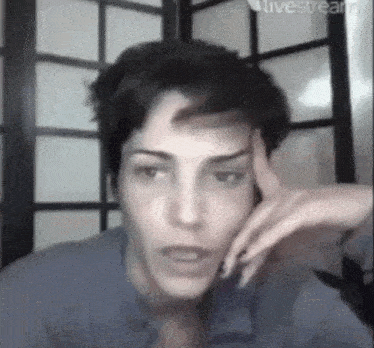 a man is holding his hand to his forehead while talking on a cell phone .