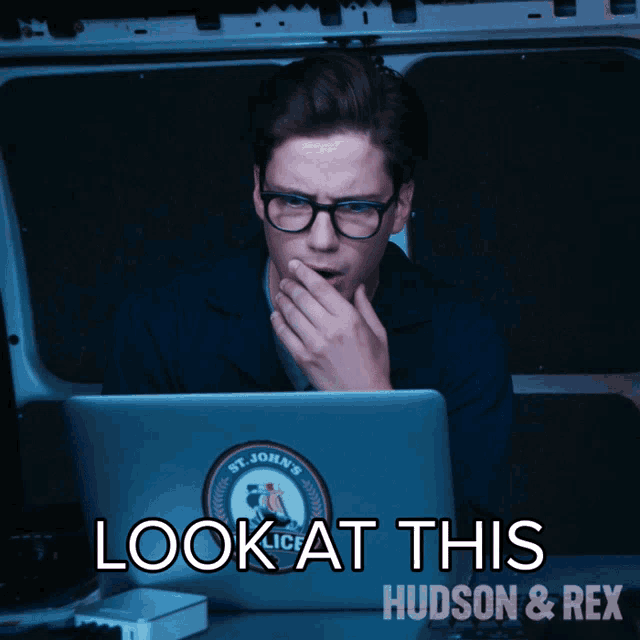 a man looking at a laptop with a st. john 's police sticker on it