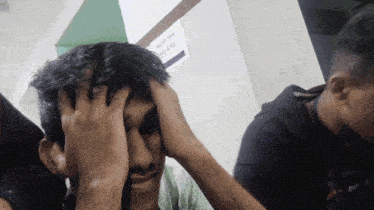 a man holds his head in front of a sign that says " adults have their face at ease "