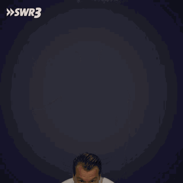 a man in a white t-shirt is making a funny face in front of a blue background with swr3 written on it