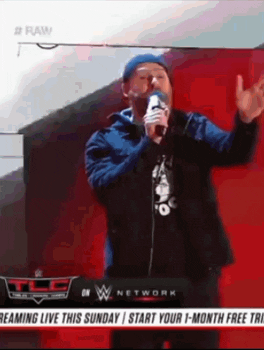 a man is singing into a microphone in front of a wwe network sign