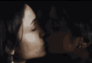 a man and a woman are kissing in a dark room in a close up .