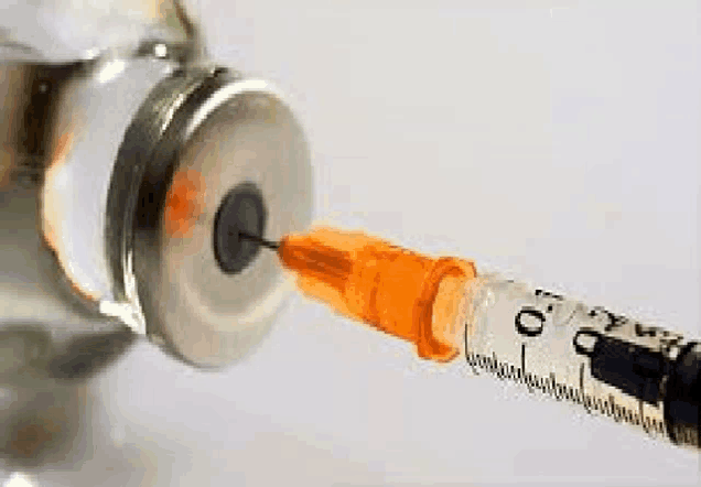 a syringe is being inserted into a bottle of medication .