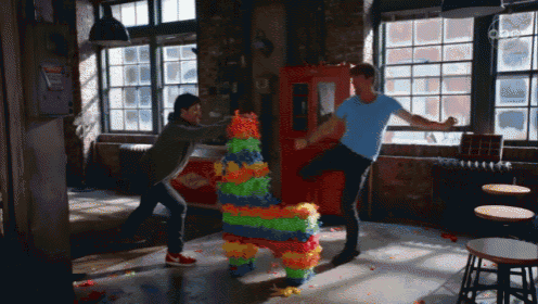two men are fighting over a colorful piñata in a room with a sign that says danger