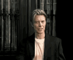 a man in a suit and a white shirt is standing in front of a door .