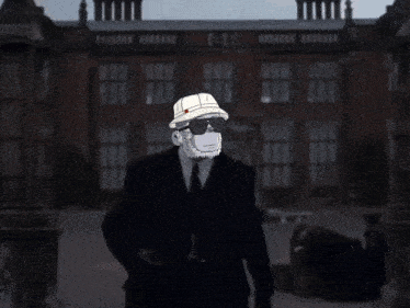 a man in a suit and hat stands in front of a building
