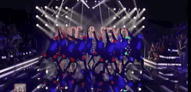 a group of people dancing on a stage with the number 14 on the bottom