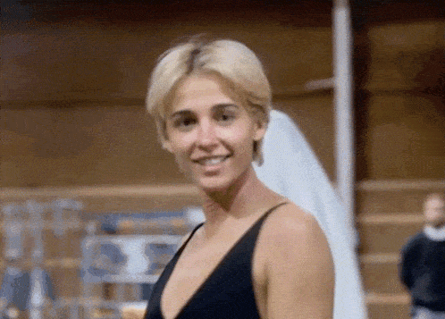 a woman wearing a black tank top is smiling and looking at the camera .