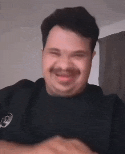 a man with a mustache is smiling at the camera .