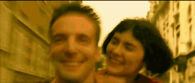 a man and a woman are smiling while standing next to each other .