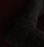 a person is laying on a bed in the dark with a shadow on the wall .