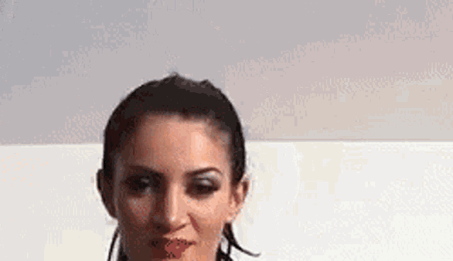 a close up of a woman 's face with a white background . she is wearing earrings and red lipstick .