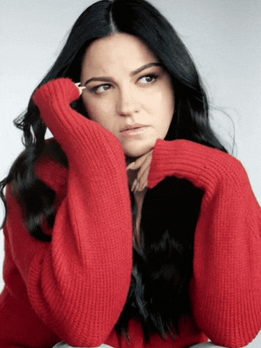 a woman in a red sweater has her hand on her head