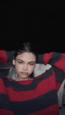 a woman in a red and black striped sweater is sitting in a dark room .
