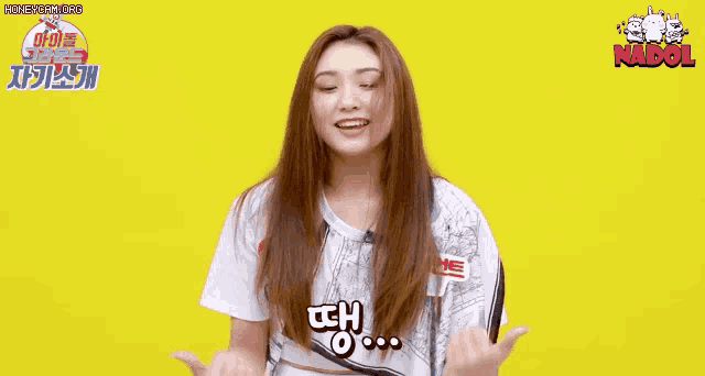 a girl with long hair is standing in front of a yellow background and holding her hair .