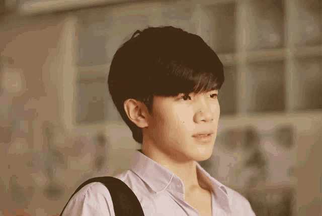 a young man wearing a purple shirt has a black backpack on his back