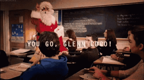 a man dressed as santa claus is standing in a classroom