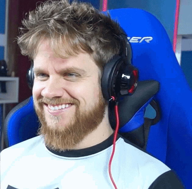 a man with a beard is wearing headphones and smiling while sitting in a blue chair