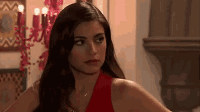 a woman in a red dress is standing in front of a chandelier .