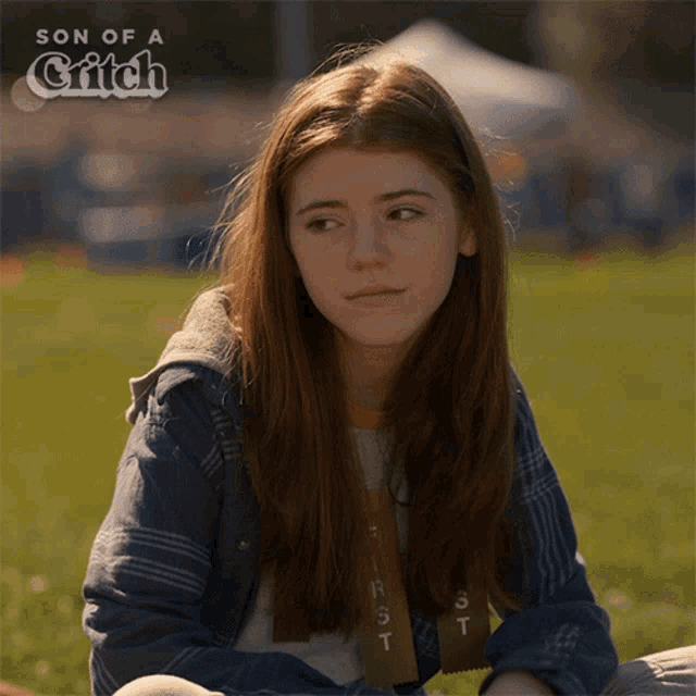 a girl with long red hair is sitting in the grass with the words son of a glitch above her