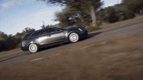 a car is driving down a road with trees in the background