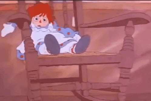 a cartoon doll is laying on a chair with a blue blanket on it .