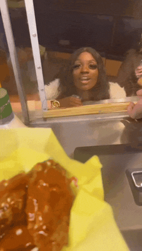 a woman in a fur coat is looking out a window at a tray of food