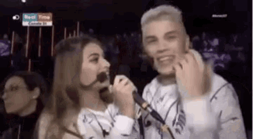 a man and a woman are singing into microphones in a dark room .