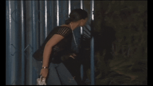 a woman in a black top is standing in front of a wall