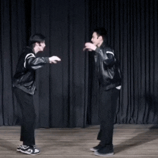 two men are dancing on a stage with a black curtain in the background