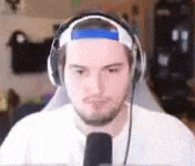 a man wearing headphones and a headband is looking at a microphone .