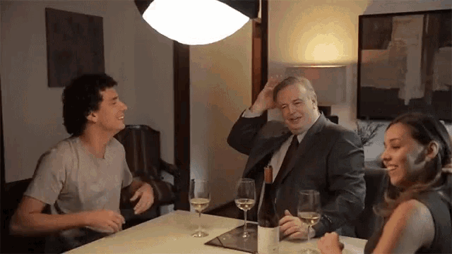 a man in a suit and tie is sitting at a table with two other people