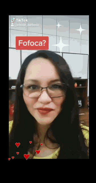 a woman wearing glasses and a yellow shirt has a red sticker on her face that says fofoca