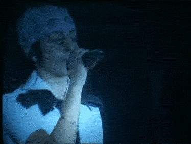 a woman wearing a bandana is singing into a microphone on a stage .