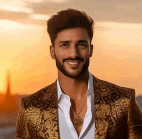 a man with a beard is wearing a gold jacket and a white shirt and smiling .