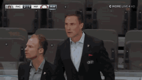 a man in a suit holds a hockey stick in front of a screen that says c-more live 4 hd
