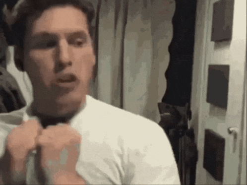 a man in a white shirt and tie is adjusting his tie in front of a mirror .