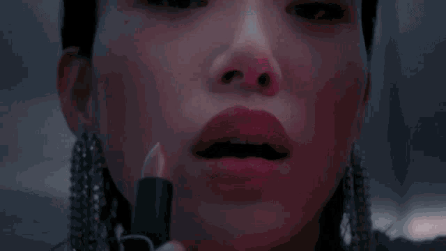a woman is applying lipstick to her lips .