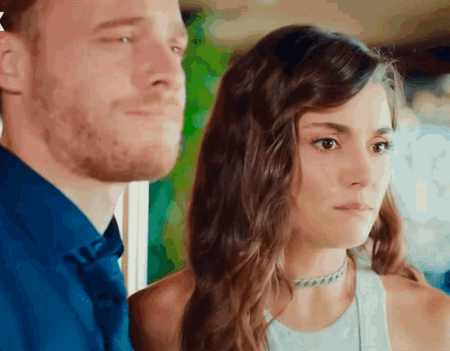 a man and a woman are standing next to each other and the woman is wearing a choker