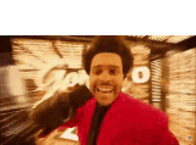 a man in a red jacket is smiling and holding a microphone in his hand .