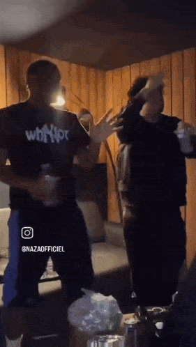 two men are dancing in a living room and one of them is wearing a shirt that says whoot