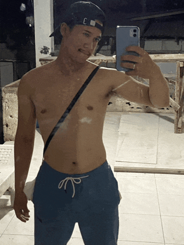 a shirtless man taking a selfie with a cell phone