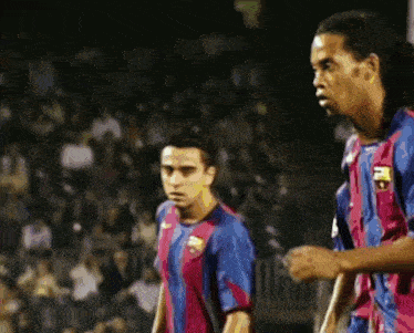 two soccer players are standing next to each other in front of a crowd .
