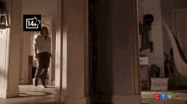a woman is walking down a hallway in a dark room with a ctv logo in the background .