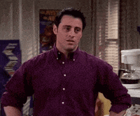 a man wearing a purple shirt is standing in a kitchen with his hands on his hips .