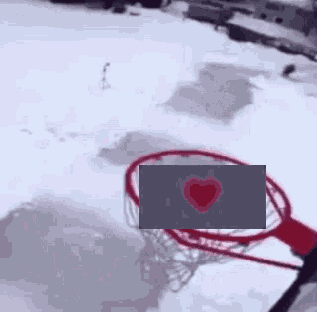a basketball hoop in the snow with a heart in the net