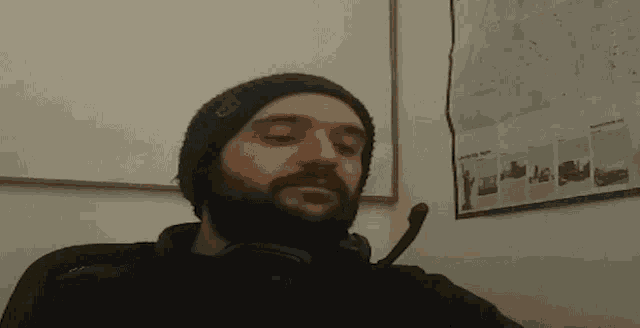 a man with a beard wearing headphones and a beanie with the letter g on it