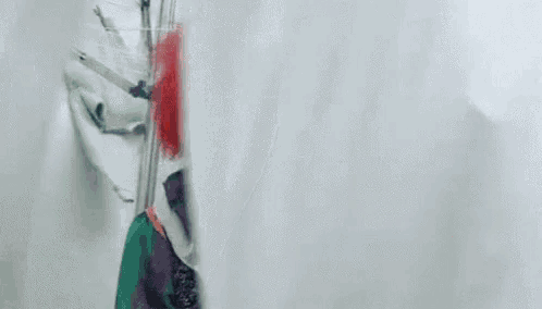 a clown is standing behind a white curtain and smiling .