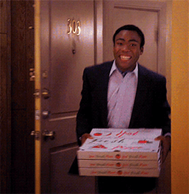 a man in a suit is carrying three pizza boxes in front of a door that says 303